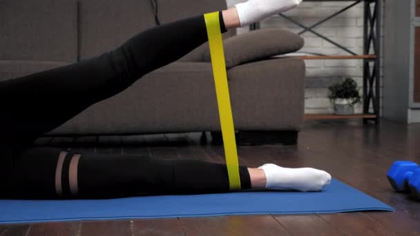 Athletic muscular woman doing legs exercise with loop band on fitness yoga mat — Stock Video