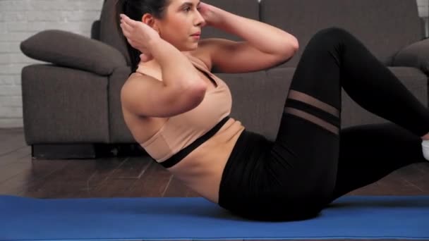 Подходящая женщина в спортивной одежде делает хрустящие упражнения для мышц живота на коврике для йоги — стоковое видео
