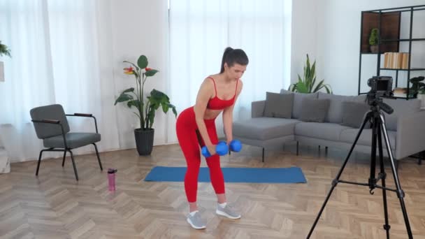 Fit kobieta fitness trener blogger robi ćwiczenia z hantlami, trening w domu — Wideo stockowe