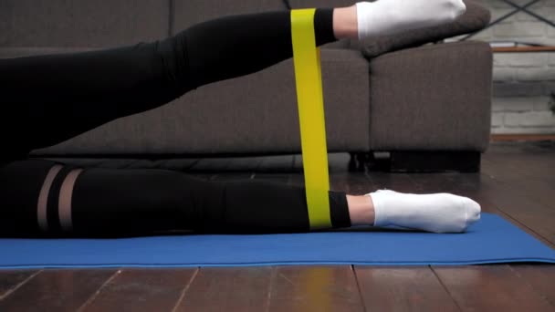 Femme athlétique sportive faisant des exercices de jambes avec bande de boucle sur tapis de fitness — Video