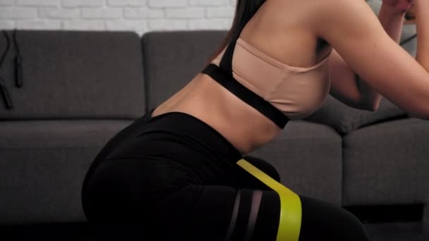 Atletische vrouw sportvrouw doet benen oefening met lus band op fitness mat — Stockvideo