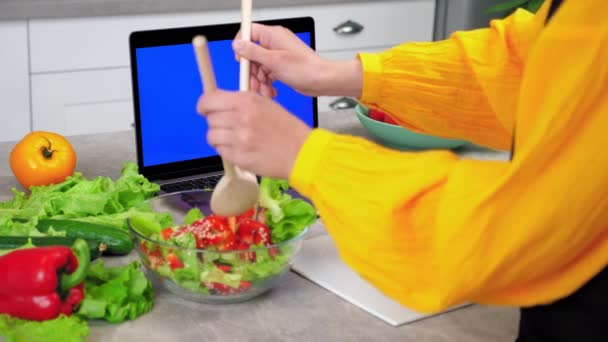 Mujer en cocina mezcla ensalada vegetariana cocida con cucharas de madera en tazón de cristal — Vídeos de Stock