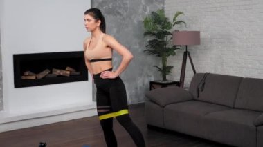 Spor giyim bölümünde formda bir kadın spor antrenmanı yapıyor. Evde yoga minderinde spor yapıyor.