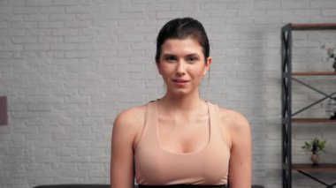 Portre atletik kaslı, gülümseyen kadın spor giyim bölümünde başını kameraya çeviriyor.