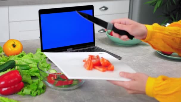 Blue Screen Laptop: Frau schneidet geschnittene Tomate vom Schneidebrett in Schüssel — Stockvideo