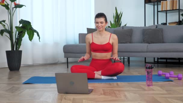 Formda bir kadın fitness eğitmenine, online video çalışmasına, web cam laptopuna selam veriyor. — Stok video
