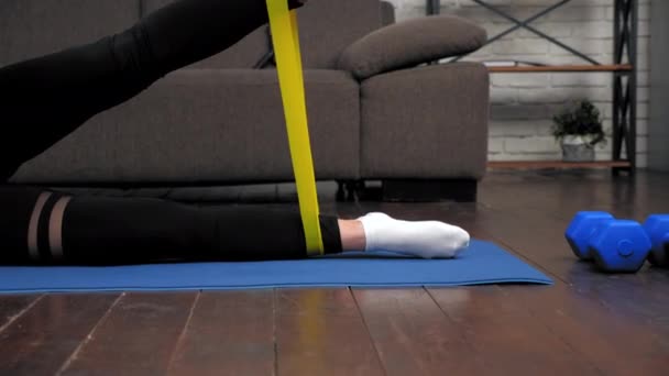 Femme athlétique sportive faisant des exercices de jambes avec bande de boucle sur tapis de fitness — Video