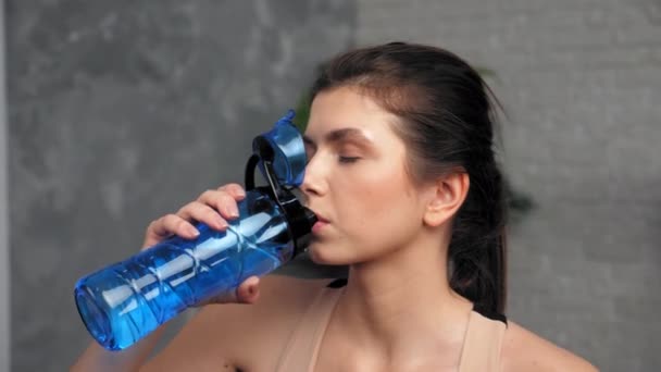 Спортивна жінка п'є воду після інтенсивних фізичних вправ вдома — стокове відео