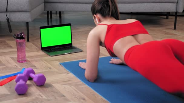 Sterke fitness vrouw doet plank op yoga mat uitziende groene scherm laptop display — Stockvideo