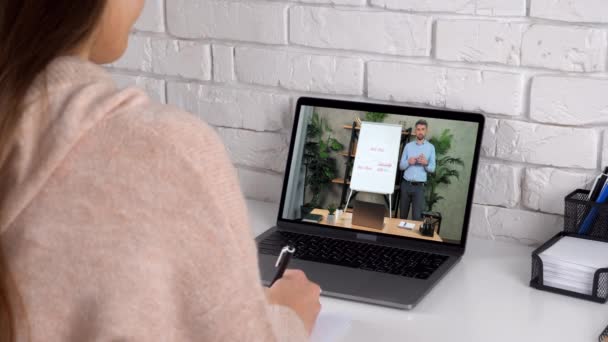 Vrouw studie thuis online video oproep laptop, schrijft in notebook luisteren leraar — Stockvideo