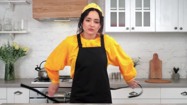 Portrait tired woman in home kitchen takes off black apron after cooking food — Stock Video