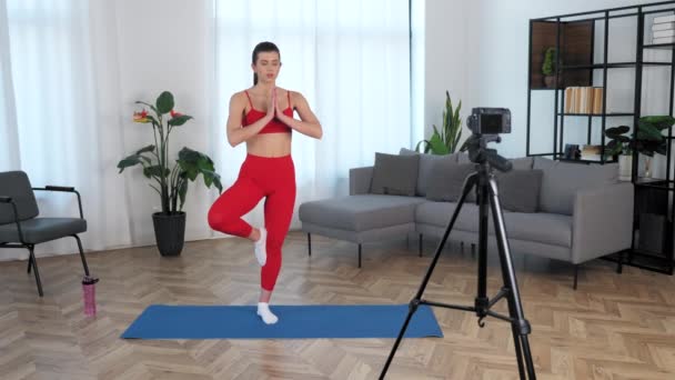 Fit vrouw fitness trainer blogger mediteert terwijl staande op yoga mat thuis — Stockvideo