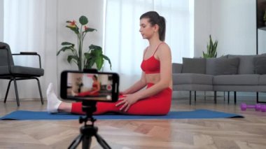 Kadın fitness eğitmeni blogcuya göre öğrencilere kas esneme hareketleri öğretiyor