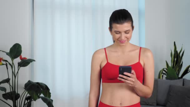 Portrait smiling athletic fit fitness woman in sportswear uses smartphone — Vídeo de Stock