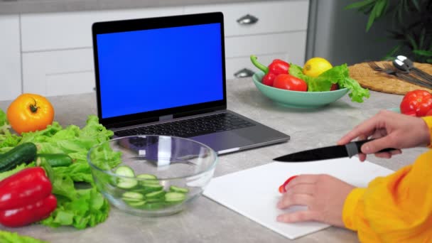 Blue screen laptop: Woman in kitchen slices pepper listen chef, online course — Vídeo de Stock