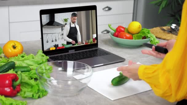 Woman in kitchen study online cooking lesson tells listen chef slices cucumber — Vídeo de Stock