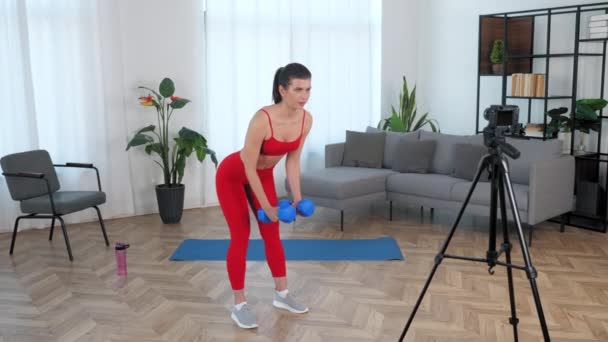 Fit γυναίκα γυμναστής blogger κάνει dumbbell άσκηση, προπόνηση στο σπίτι — Αρχείο Βίντεο