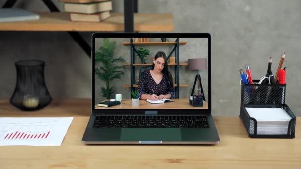 Laptop står på bordet display med affärskvinna på kontoret skriver i anteckningsbok — Stockvideo
