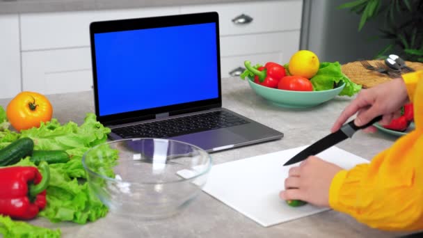 Синій екран ноутбук: жінка на кухні вітає скибочки огірка каже вчительці шеф-кухаря — стокове відео