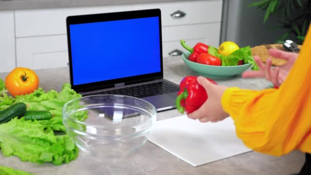 Блакитний екран ноутбук: жінка на домашній кухні показує болгарський перець в веб-камеру каже шеф-кухарю — стокове відео