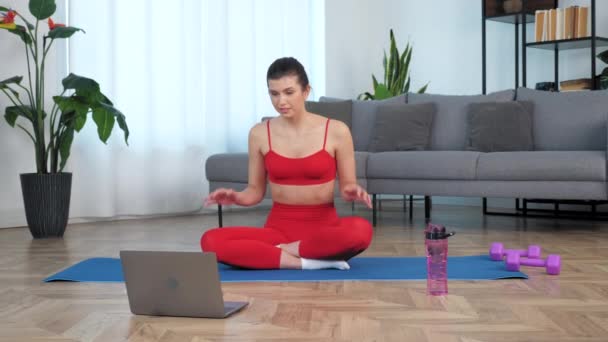 Fit kvinna sitter på yogamattan berättar med fitness tränare, studera online — Stockvideo