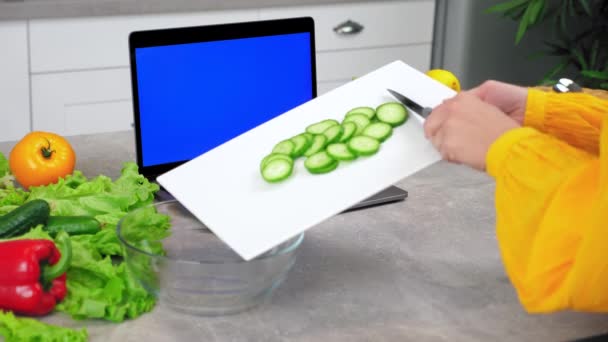 Blue Screen Laptop: Frau schneidet Gurkenscheiben vom Schneidebrett in Schüssel — Stockvideo