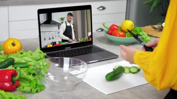 Kobieta nauka online wideo rozmowy laptop mówi szef kuchni plastry ogórek słuchać nauczyciel — Wideo stockowe