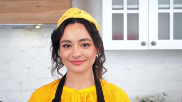 Primer plano sonriendo hermosa ama de casa mirando a la cámara en casa cocina moderna — Vídeo de stock