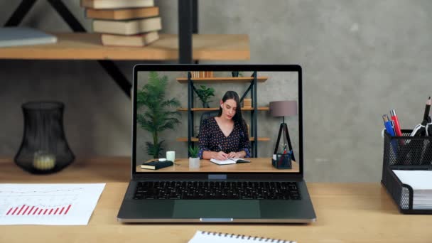 Laptop staan op tafel display met zakenvrouw in het kantoor schrijft in notebook — Stockvideo