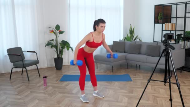 Apto mulher treinador de fitness blogger fazendo exercício dumbbell, treino em casa — Vídeo de Stock