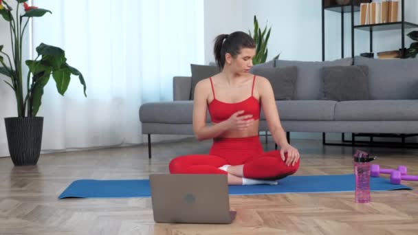 Frau sitzt auf Yogamatte sagt Fitness-Trainer zeigt, welche Muskeln er aufbauen will — Stockvideo