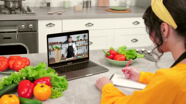 Hombre chef en pantalla portátil enseña ama de casa elimina las verduras de la bolsa de papel — Vídeos de Stock