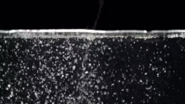 Akvaryumda yavaş hareket eden su akımı siyah bir arkaplanda düşer.