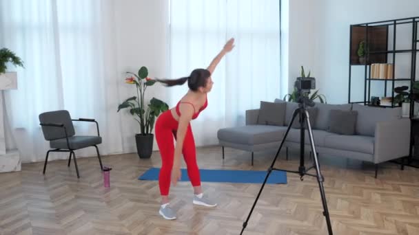 Apto mulher treinador de fitness blogger fazendo exercício de aquecimento em casa — Vídeo de Stock