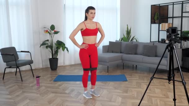 Passande kvinna fitness blogger berättar student gör motion för ben med ögla band — Stockvideo