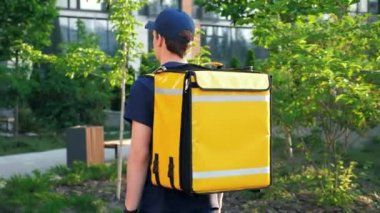 Termal sırt çantalı genç kurye sokakta yürüyor.