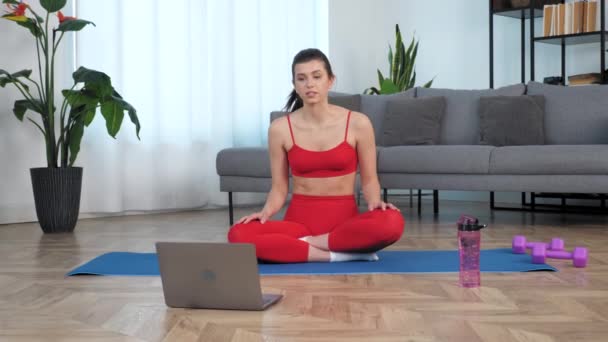 Donna in forma si siede sul tappetino yoga dice allenatore di fitness, studio online video chiamata laptop — Video Stock