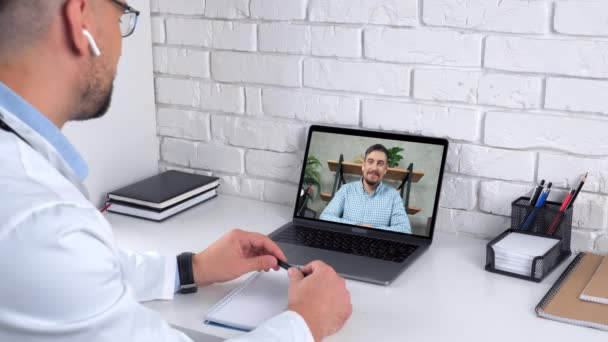 Orvos a kórházi irodában üdvözöl mondja beteg online video hívás webkamera laptop — Stock videók