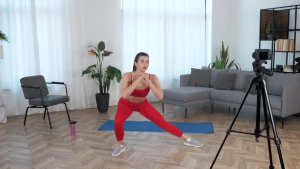 Fit vrouw fitness trainer blogger doet warming-up oefening workout in modern huis — Stockvideo