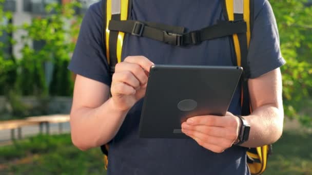 Cercano entrega de comida joven mensajero con mochila térmica utiliza tableta — Vídeos de Stock