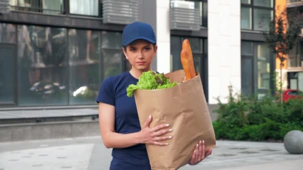 Entrega de comida mensajero mujer con bolsa de papel comestibles para entregar orden cliente — Vídeo de stock