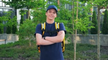 Gülümseyen genç adam kurye yiyecek teslimatını termal sırt çantasıyla büyüt.