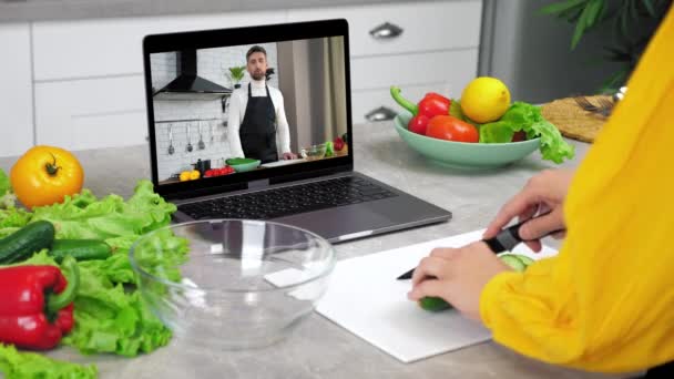 Woman in kitchen study online cooking course slices cucumber listen chef teacher — Stock Video