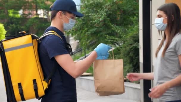 Teslimatçı, maskeli kadın müşteri siparişi vermek için maske ve eldiven takıyor. — Stok video