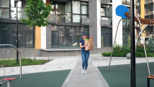 Entrega de comida mensajero mujer con bolsa de papel comestibles para entregar orden cliente — Vídeo de stock