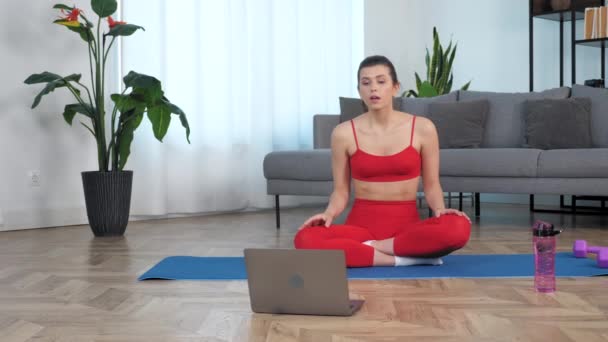 Thoughtful fit kvinna sitter på yogamattan lyssna prata fitness tränare, studera online — Stockvideo