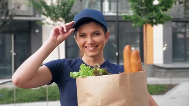 Close up sorrindo entrega de alimentos mulher correio mantém saco de papel com mantimentos — Vídeo de Stock