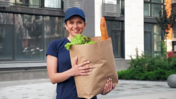Correio sorridente da mulher da entrega com mantimentos do saco de papel para entregar o cliente da ordem — Vídeo de Stock