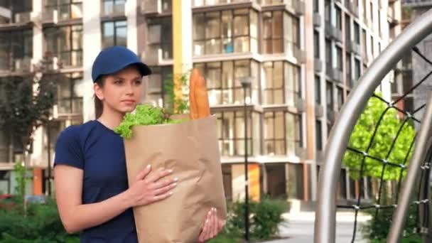 Sipariş müşterisini teslim etmek için kese kağıdı taşıyan kadın kurye. — Stok video