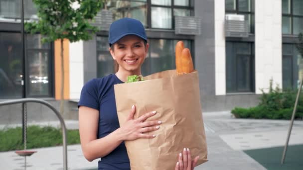 Portrét usmívající se dodávka potravin žena kurýr drží papírový sáček s potravinami — Stock video